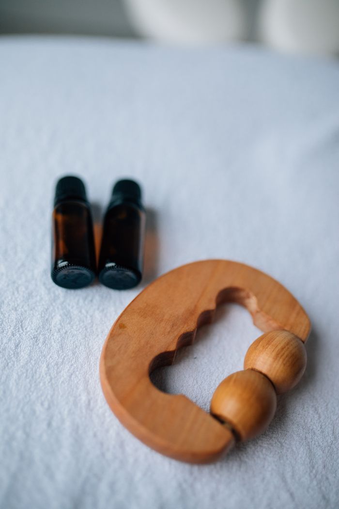 Home Close-up of essential oil bottles and a wooden massager on a soft surface.