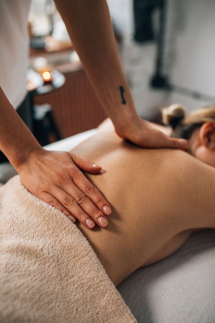 Home Close-up of hands massaging a person's back in a tranquil spa setting, promoting relaxation and wellness.